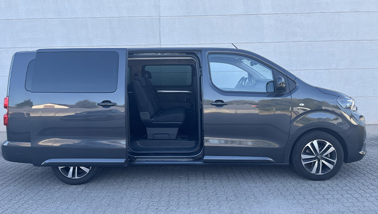 Eine dunkle Großraumlimousine mit geöffneter Schiebetür und sichtbarem Sitzplatz
