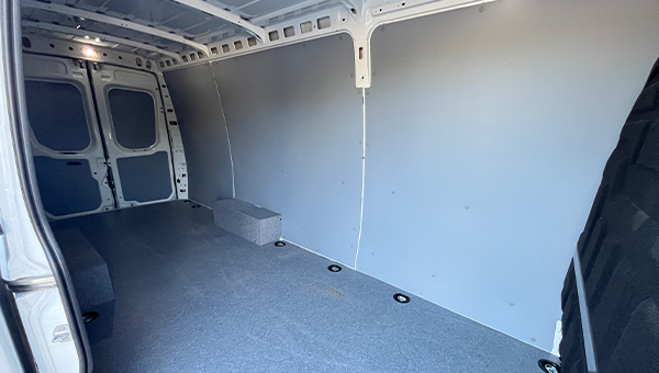 Ein leerer heller Transporterinnenraum mit grauen Wänden und Boden, sauber und geräumig